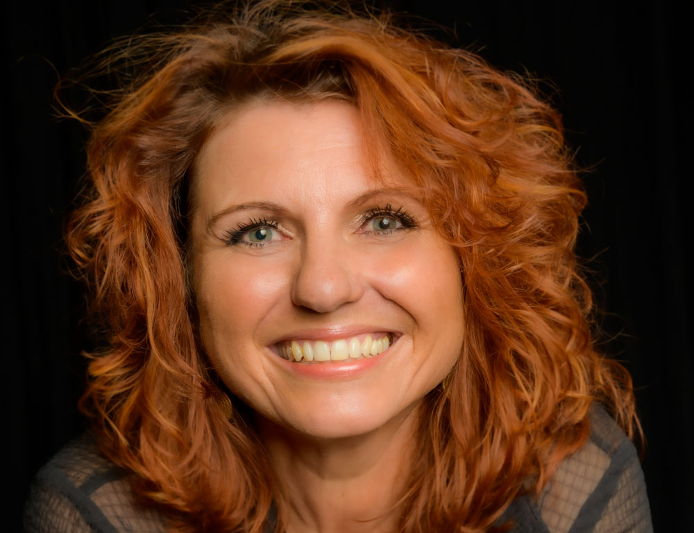 Mara Kaiser lachend im Portrait vor dunklem Hintergrund